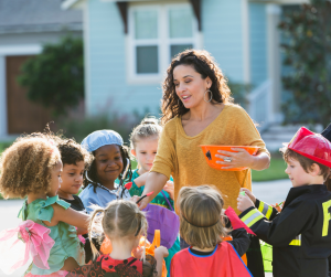 Woman Handing Candy to Trick or Treaters