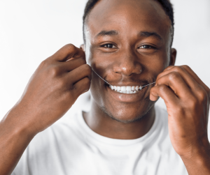 Man smiling flossing teeth