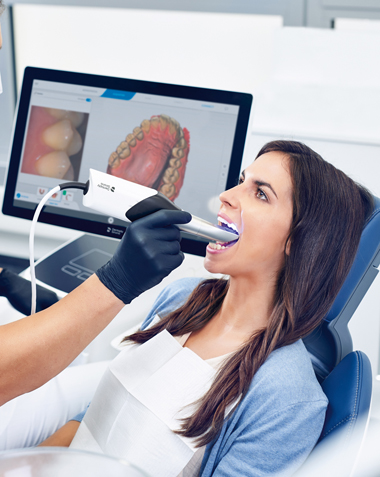Woman in dental shair getting her teeth scanned for a CEREC same-day crown