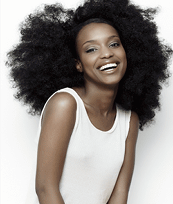African American woman with natural hair smiling - for informatioin on Moline teeth whitening from Dr. Goebel